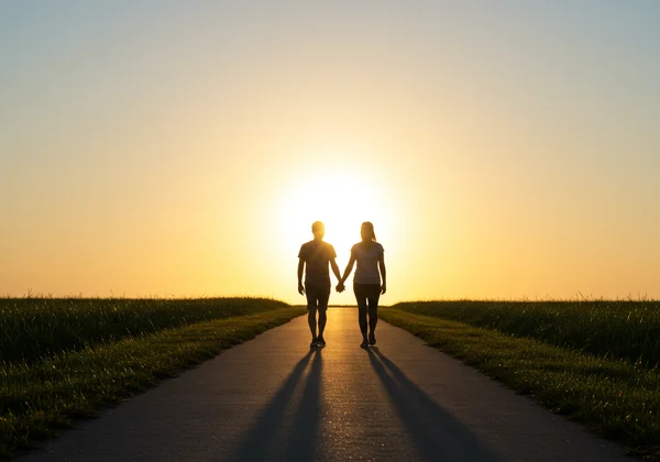 A couple walking towards a sunrise, a peaceful partnership.
